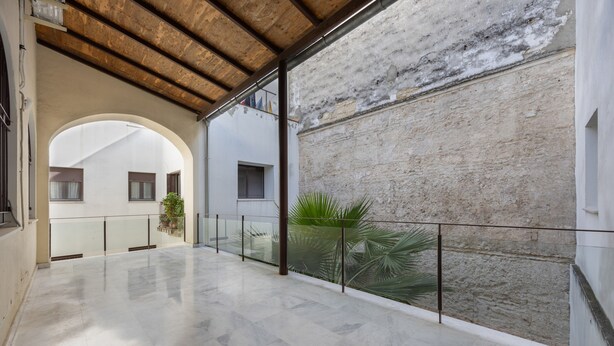 A spacious indoor area with a marble floor, a glass railing, and a view of a building with a stone facade. - Centrica Jerez Apartment with Shared Terrace, Wi-Fi, and Air Conditioning (Jerez de la Frontera)
