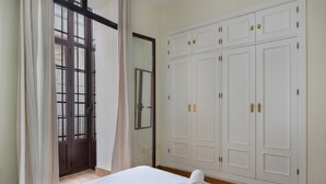 A bedroom with a bed, a wardrobe, and a door leading to a balcony. - Centrica Jerez Apartment with Shared Terrace, Wi-Fi, and Air Conditioning (Jerez de la Frontera)