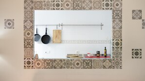 A kitchen with patterned tiles, hanging pots, a wooden cutting board, and a shelf with kitchen items. - Centrica Jerez Apartment with Shared Terrace, Wi-Fi, and Air Conditioning (Jerez de la Frontera)