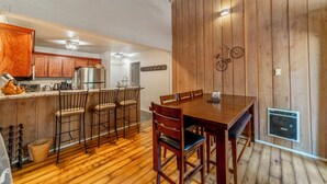 A kitchen with wooden cabinets, a stainless steel refrigerator, and a dining area with a wooden table and chairs. - Updated Ski-Back Condo w/ Garage at Canyon Lodge (Mammoth Lakes)