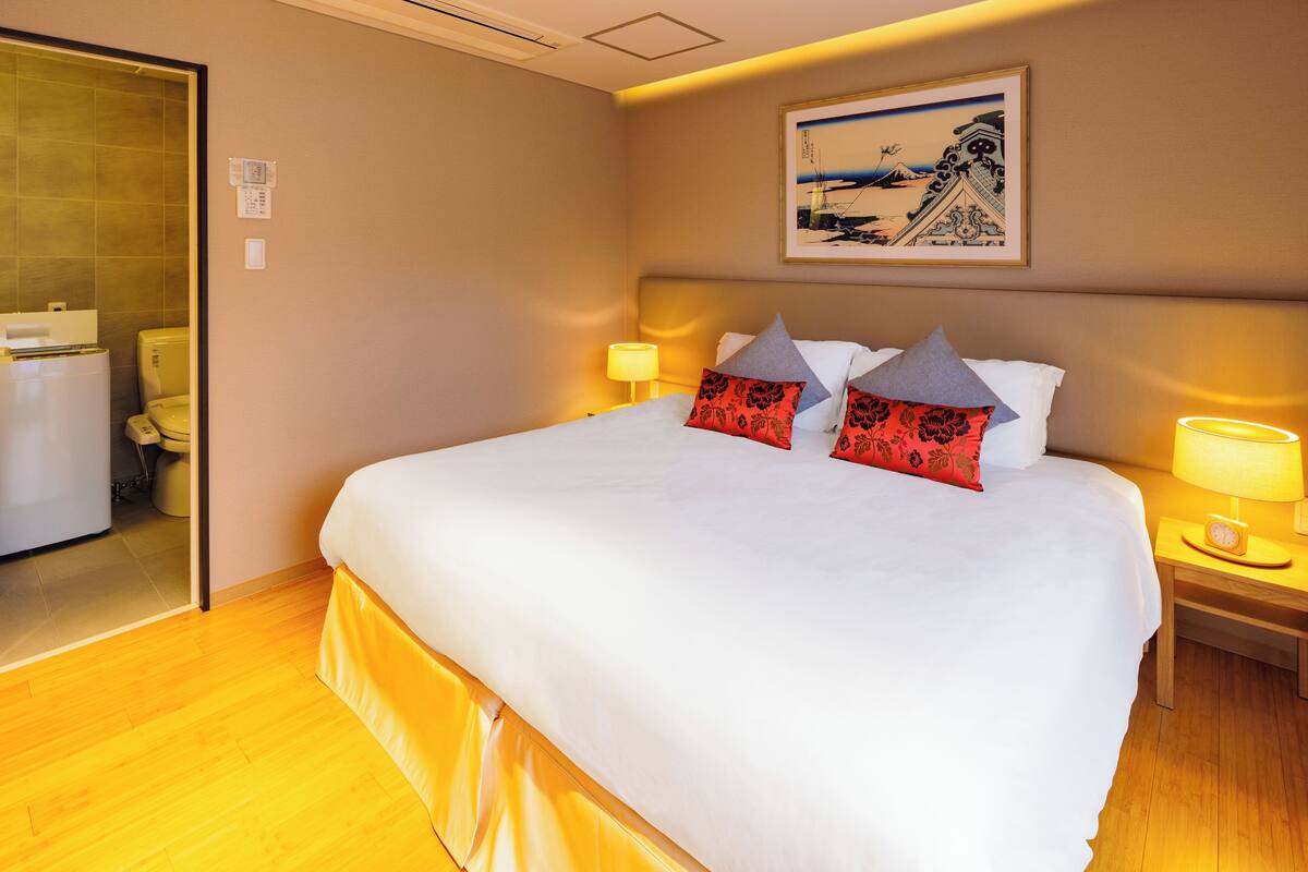 Een hotelkamer met een groot bed, twee bedlampen, een ingelijst schilderij aan de muur en een houten vloer.