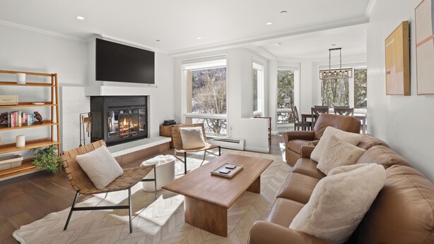 A modern living room with a fireplace, leather sofas, a wooden coffee table, and a bookshelf. - Chamonix 30 | Snowmass Ski-In/Ski-Out Condo w/Shared Pool/Hot Tub/Private Washer/Dryer/Gym/WiFi (Snowmass Village)