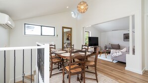 A modern living space with a dining area, a sofa, and a television.