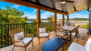 Une terrasse extérieure couverte, aménagée avec des meubles en osier, une table et un barbecue.