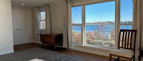 A spacious room with large windows offering a view of a body of water and trees.