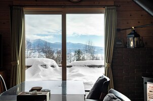 A room with a large window overlooking a snowy landscape with mountains.
