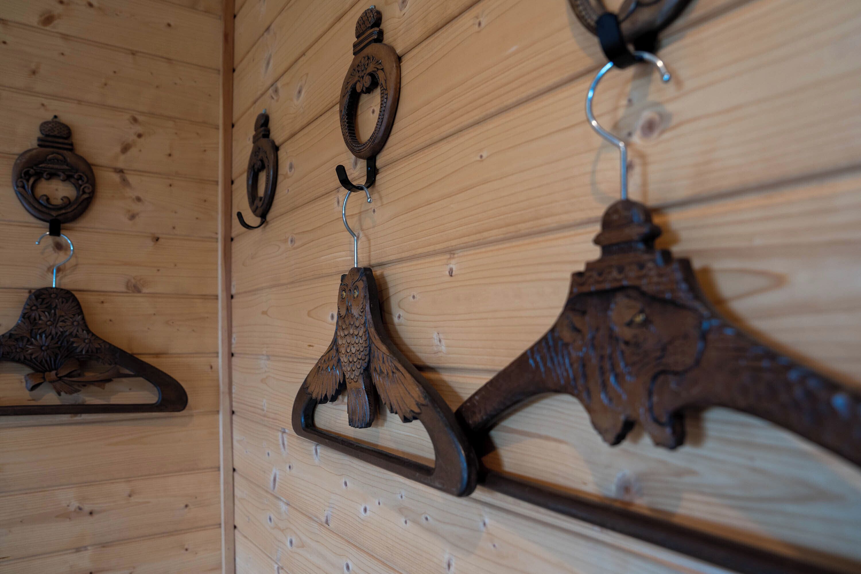 A wooden wall with three metal coat hooks.