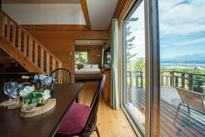A wooden interior with a dining area, a staircase, and a balcony with a view. - BEST VIEW (Nakafurano)