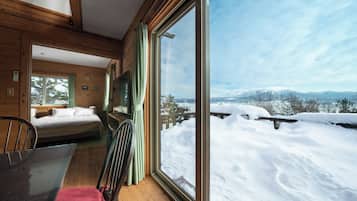 A wooden cabin with a large window overlooking a snowy landscape.