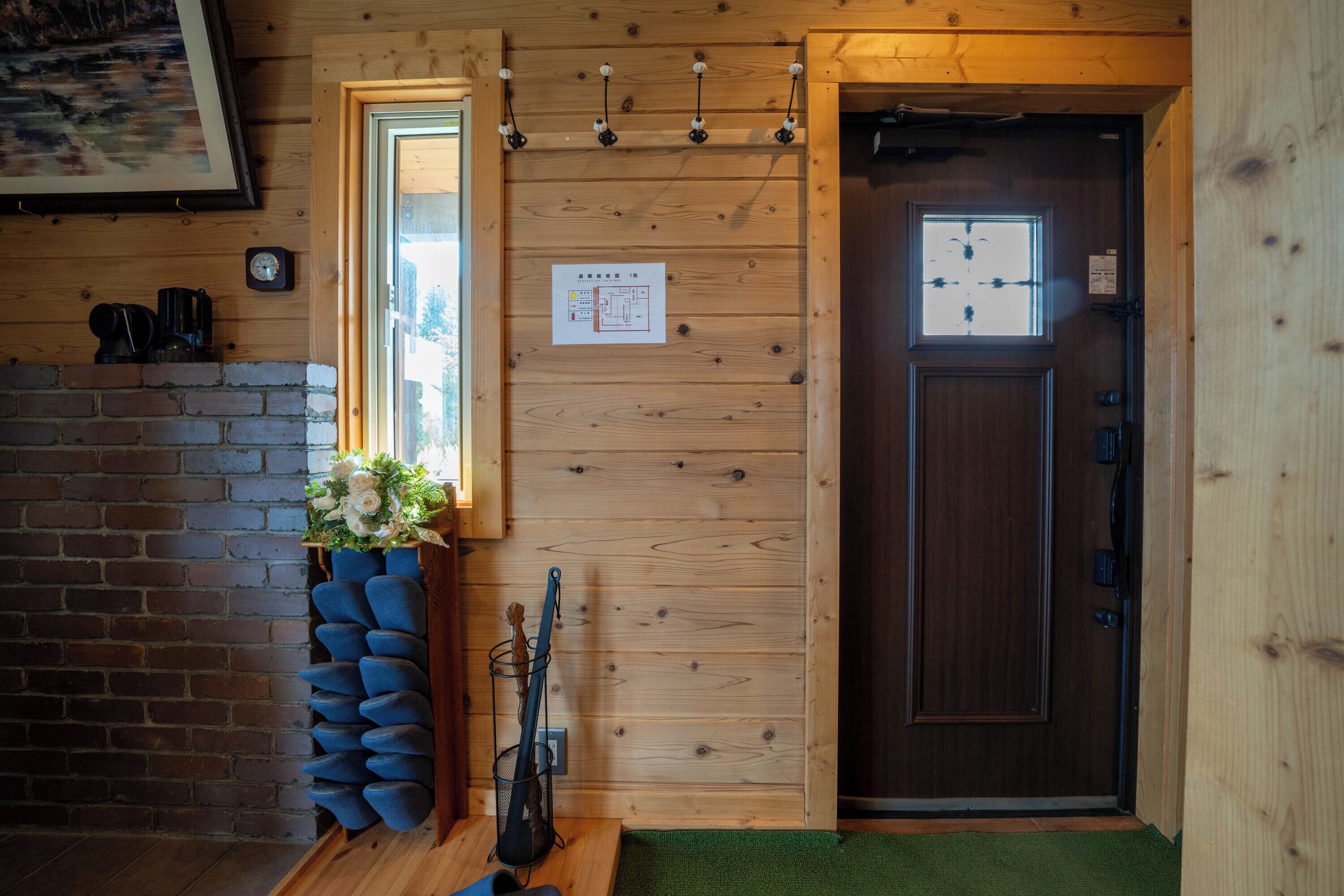 A wooden interior with a brick wall, a wooden door, a window, and a wall-mounted light fixture.