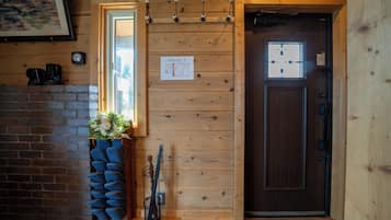 A wooden interior with a brick wall, a wooden door, a window, and a wall-mounted light fixture.