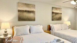 A hotel room with two beds, white bedding, a ceiling fan, and artwork on the walls. - 7BR Comfort Haven For 16 I Next to Tinker I EC (Midwest City)