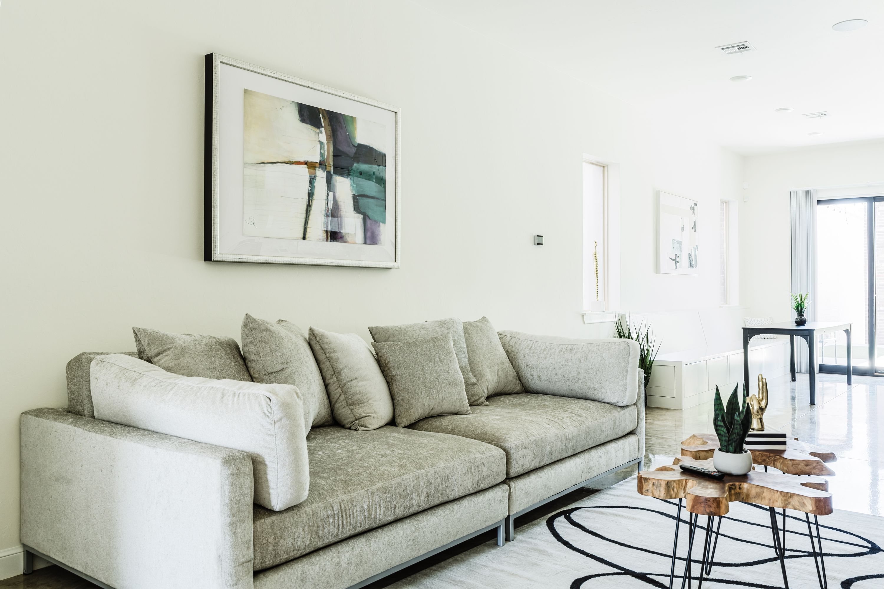 Ein modernes Wohnzimmer mit einem grauen Sofa, einem Couchtisch mit einer Pflanze und Kunstwerken an der Wand.