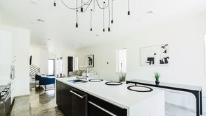 A modern kitchen with a central island, stainless steel appliances, and a staircase leading to another level. - Cozy Getaway Perfect for 10 Prime Location NW6 (Oklahoma City)