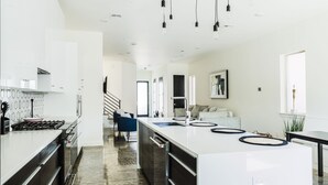 A modern kitchen with a central island, built-in appliances, and a staircase leading to another level. - Cozy Getaway Perfect for 10 Prime Location NW6 (Oklahoma City)