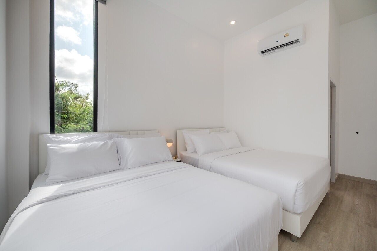 A modern bedroom with two beds, a large window, and an air conditioning unit.