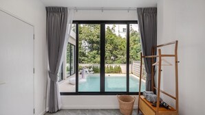Ein Schlafzimmer mit großem Fenster, einem Holzregal und einem Korbwannenkorb.
