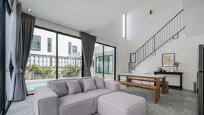 Ein modernes Wohnzimmer mit einem Ecksofa, einer Holzbank und einer Treppe.