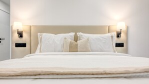 A neatly made bed with two pillows and two wall-mounted lamps on either side.
