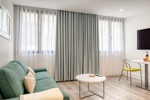 Relax in this inviting space with a green sofa, round table, and flat-screen TV.