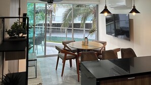 A modern kitchen with a dining area, large windows, and a ceiling fan.