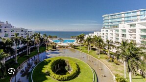 A resort with a pool, palm trees, and a view of the ocean.