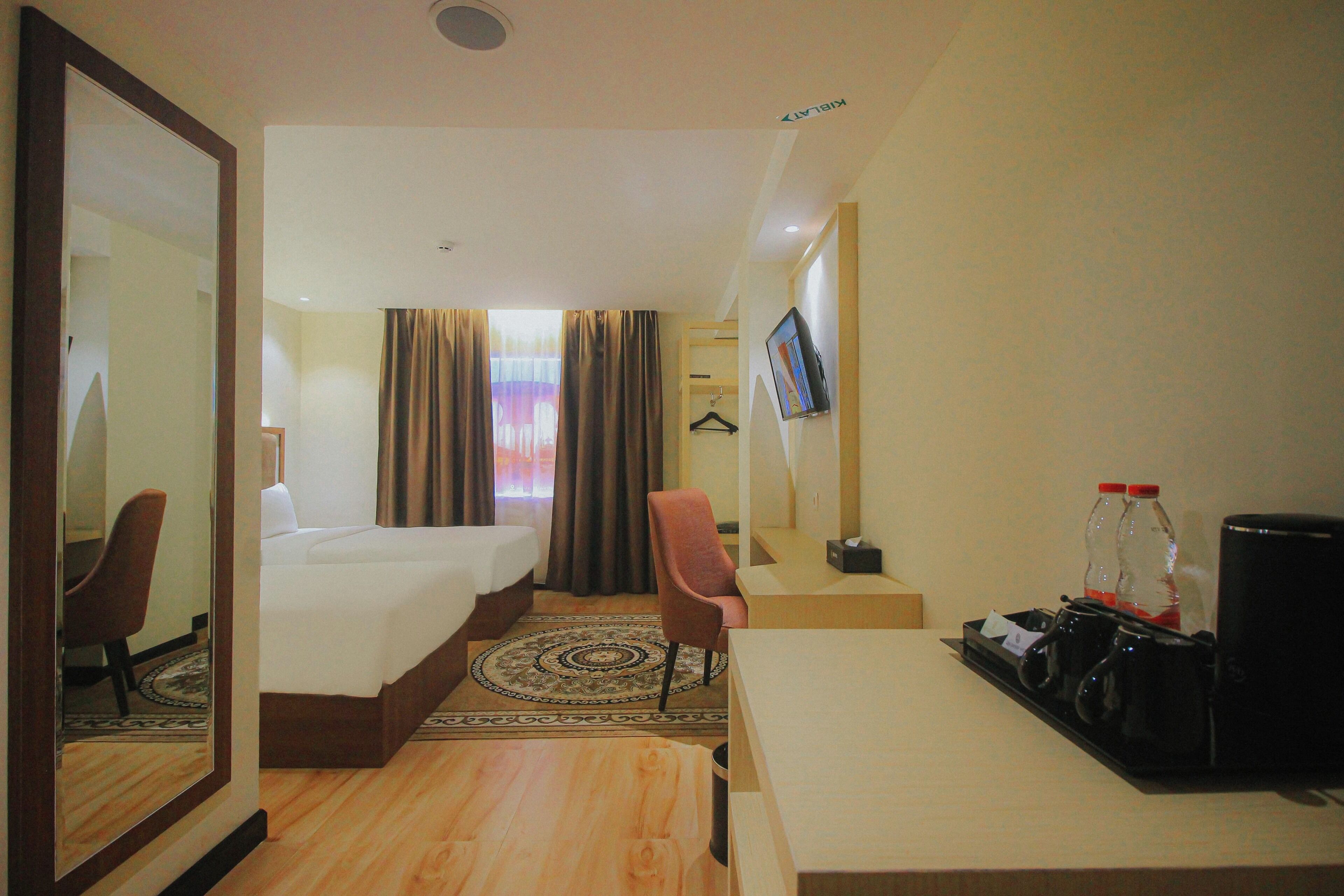 A hotel room with a bed, a desk, a chair, a TV, and a coffee machine.
