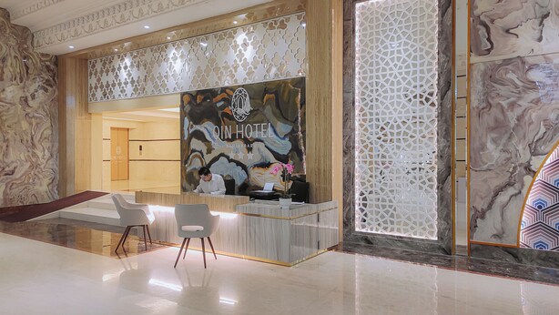 Een hotel receptie met een marmeren balie, een receptionist en een modern interieur.