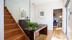 A modern interior with a wooden staircase, a desk with a laptop, and a bed in the adjacent room. - Little Alfie, North Sydney Isyd (North Sydney)