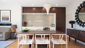 A modern kitchen with a dining area, wooden cabinets, and a large mirror. - Little Alfie, North Sydney Isyd (North Sydney)
