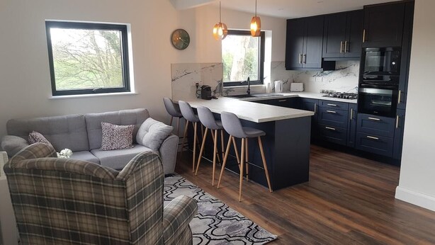 A modern kitchen with dark cabinets, a central island, and bar stools.