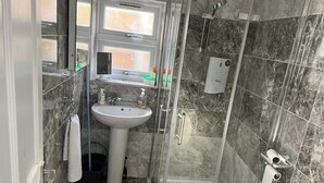 A bathroom with a sink, a window, a shower, and a toilet. - Ldn Studio-Free Parking-15 min to Elizabeth Line (Dagenham)