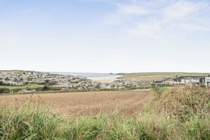 A coastal town with a beach, houses, and a field in the foreground.