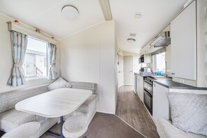 A compact RV interior with a kitchenette, a dining area, and a seating space.