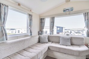 A room with a large window, a sofa, and a lamp.