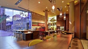 Un restaurante moderno con una larga mesa de madera, asientos en la barra y un tablero de menú a la vista.
