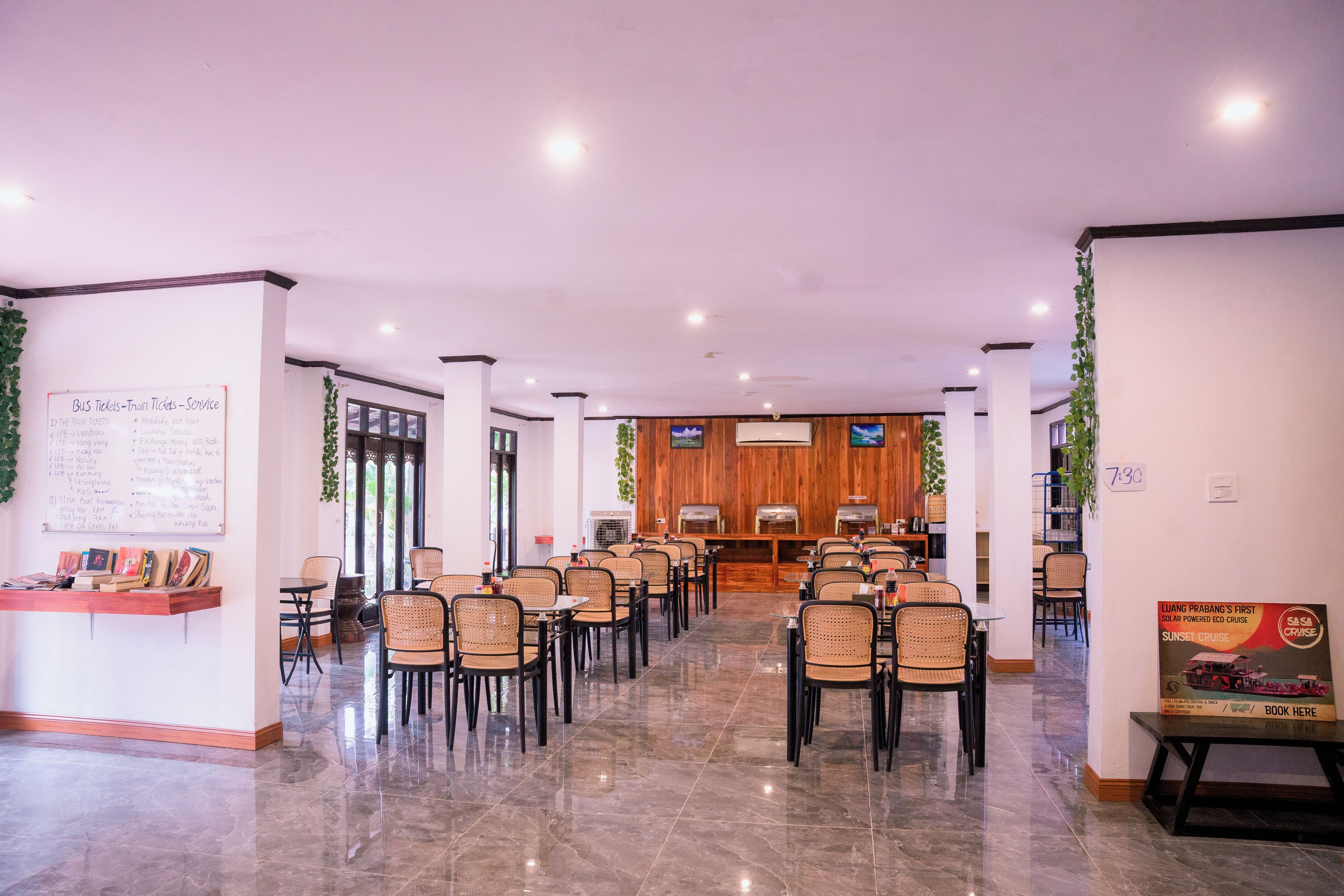 A spacious indoor area with rows of tables and chairs, a reception desk, and a wall with a menu board.