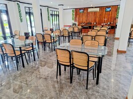 A spacious dining area with multiple tables and chairs, a wooden accent wall, and a television screen.