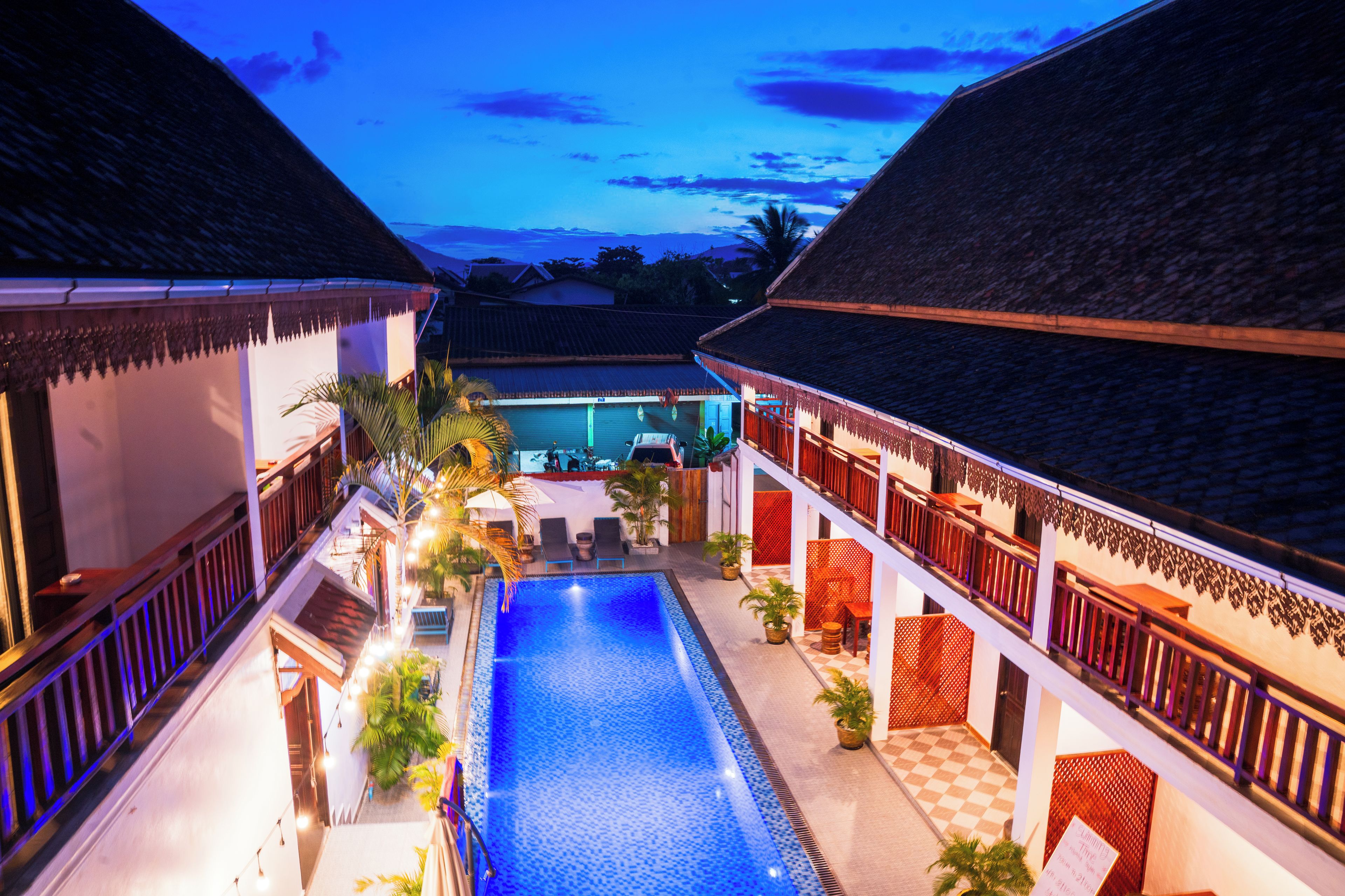 A pool area with a checkered floor, surrounded by buildings with thatched roofs and wooden railings.