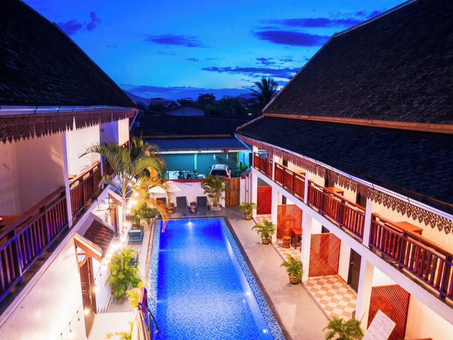 A pool area with a checkered floor, surrounded by buildings with thatched roofs and wooden railings.