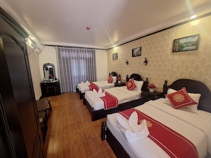 A hotel room with two beds, a wooden floor, a mirror, a desk, and a window with curtains. - LuangPrabang Pavilion Hotel & Travel (Luang Prabang)