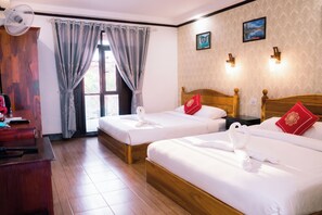 Habitación de hotel con dos camas, un escritorio, una silla, un ventilador y una ventana con cortinas.