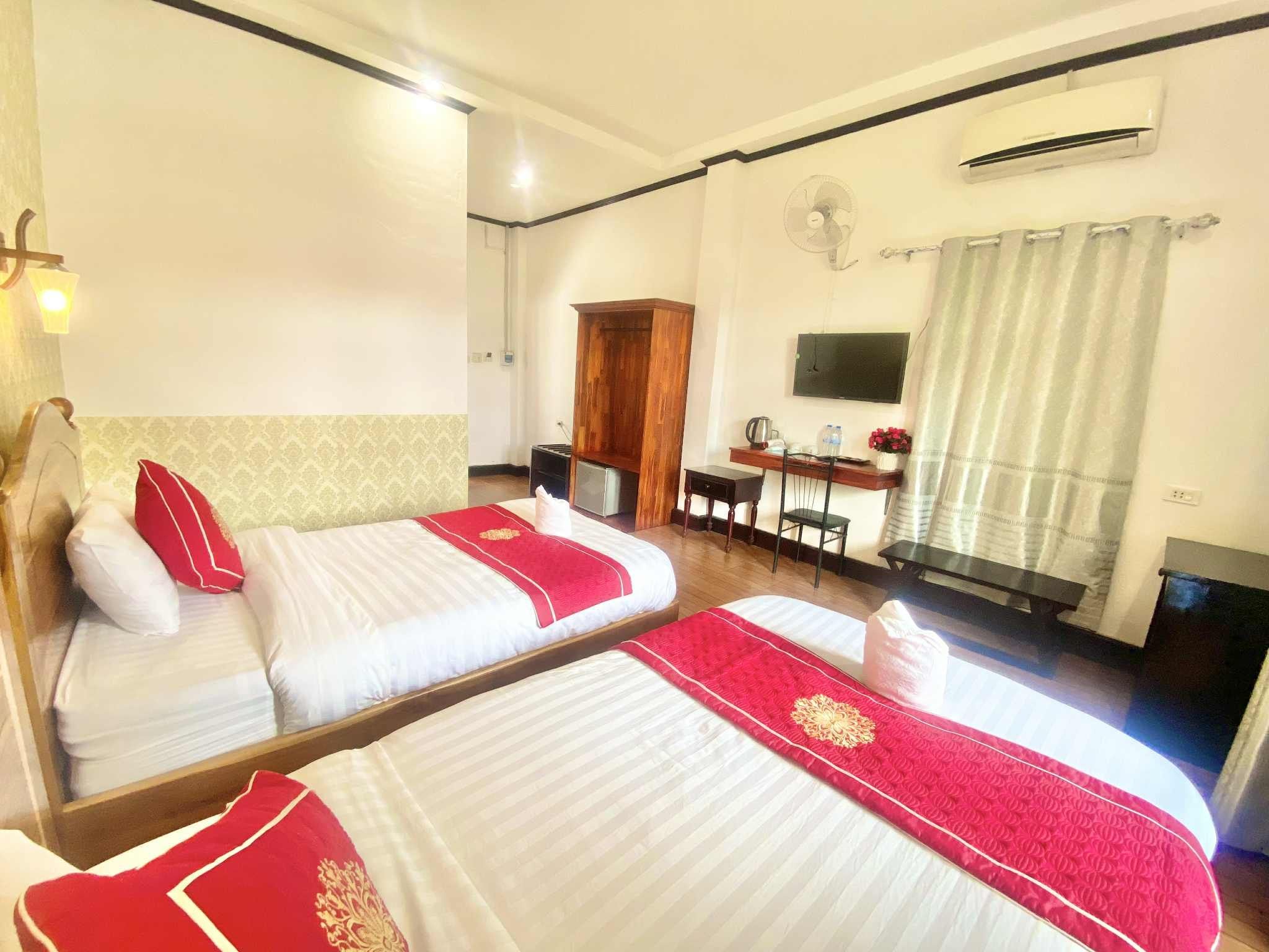 Habitación de hotel con dos camas, un escritorio, una silla, un televisor y un equipo de aire acondicionado.