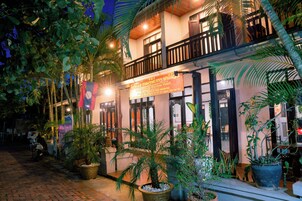A hotel with a balcony, potted plants, and a signboard.