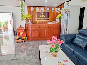 A hotel reception area with a wooden reception desk, a black leather sofa, a marble floor, and a reception sign. - LuangPrabang Pavilion Hotel & Travel (Luang Prabang)
