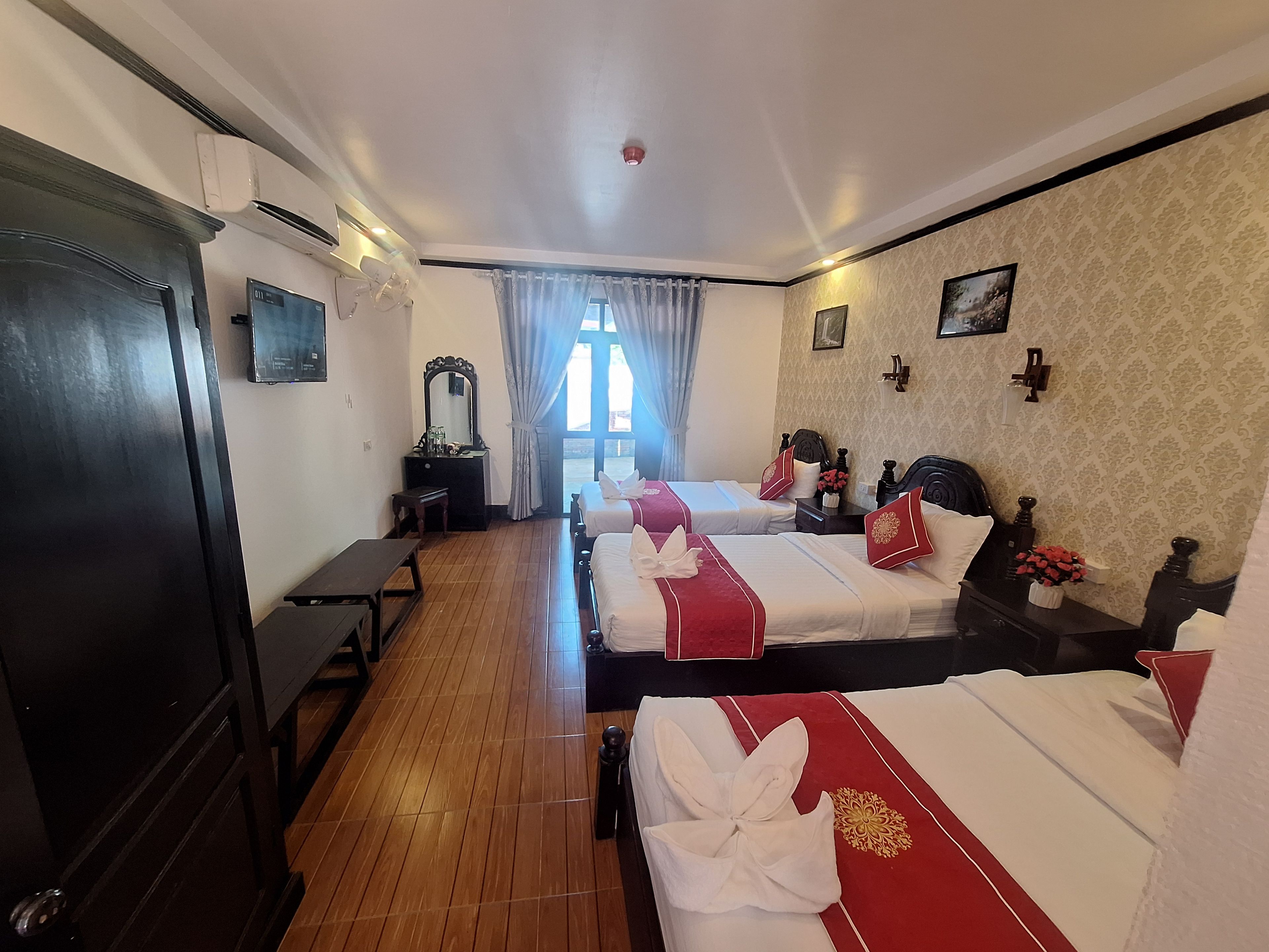 Una habitación de hotel con dos camas, un escritorio, un tocador y una ventana con cortinas.