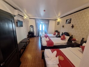 A hotel room with two beds, a desk, a dresser, and a window with curtains.