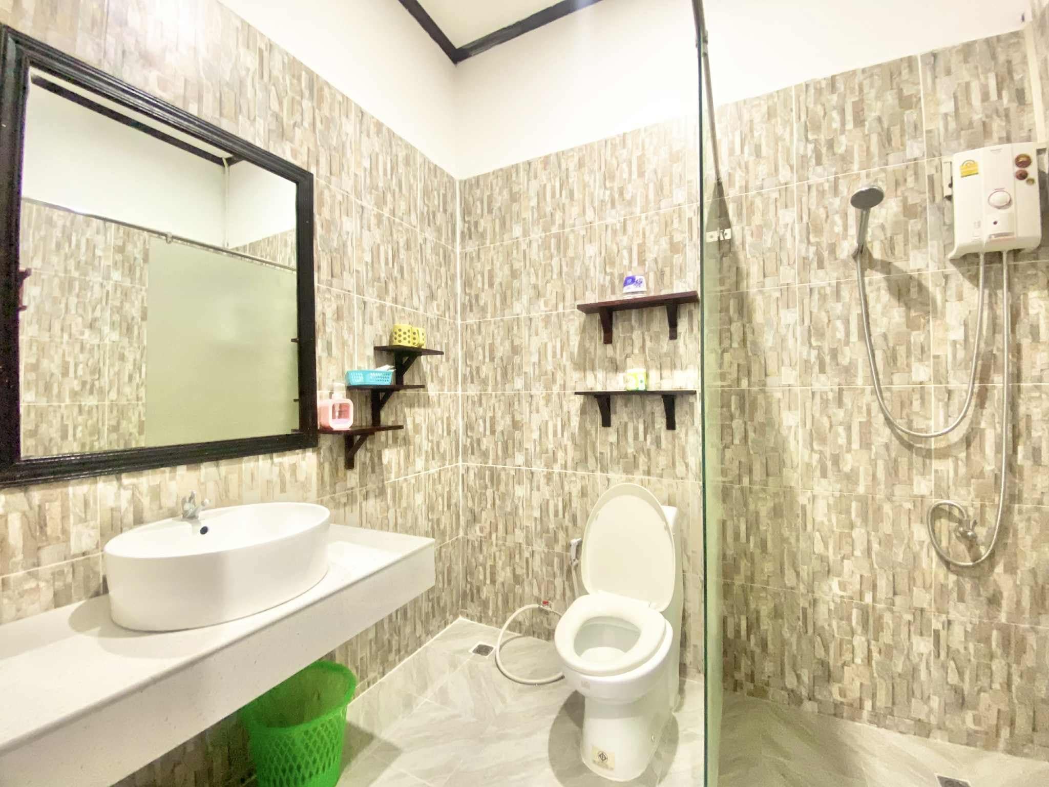 A bathroom with a white sink, a toilet, a shower, and a mirror.