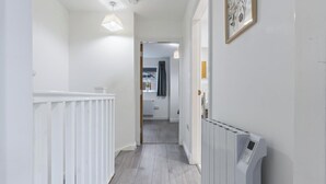 A narrow hallway with a white radiator, a ceiling light, and a door leading to another room.