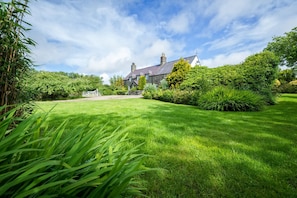 Une grande maison avec une pelouse bien entretenue et une clôture blanche en premier plan.